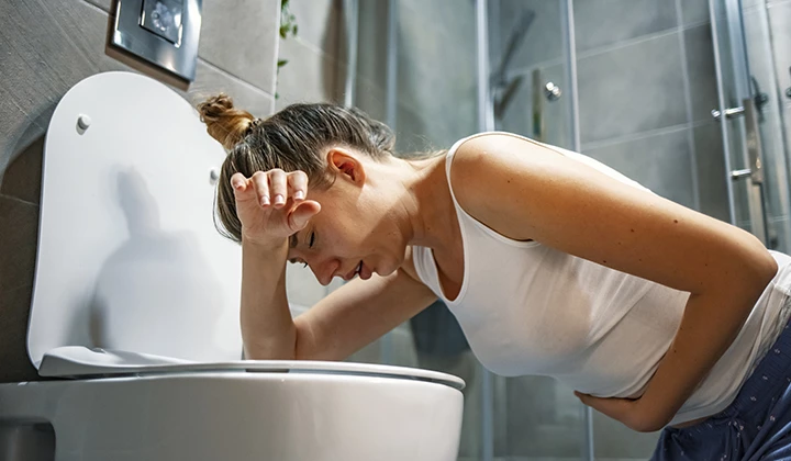 Frau hockt vor Toilette Lebensmittelunverträglichkeit als Erbrechen-Ursachen